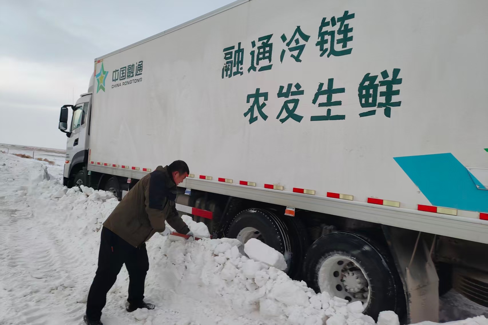 道路被雪隐没,驾驶员配送途中停车铲雪.jpg